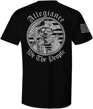 Large graphic of a skull-faced patriot in a tricorn hat and tactical gear with rifles, standing in front of a blacked-out American flag; 'Allegiance' arched above and 'We The People' curved below on the back of a black t-shirt